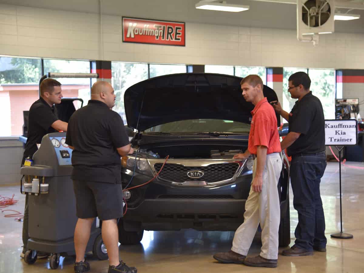 Automotive instructor Brandon Dean stands with students around a car in the Automotive Technology lab.