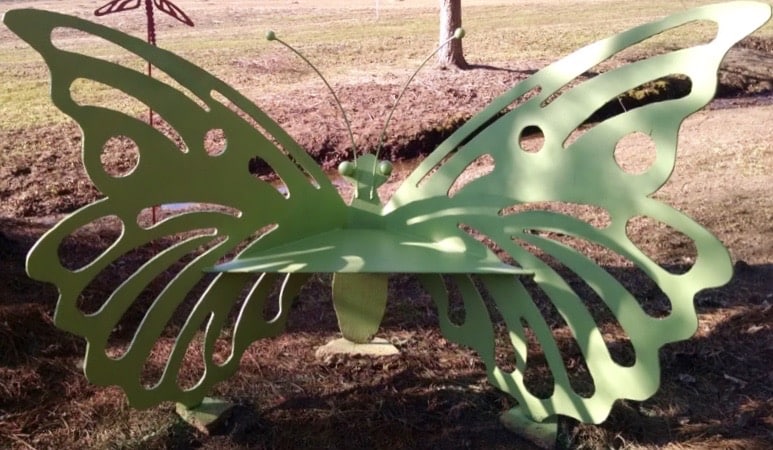 A green metal bench in the shape of a butterfly.