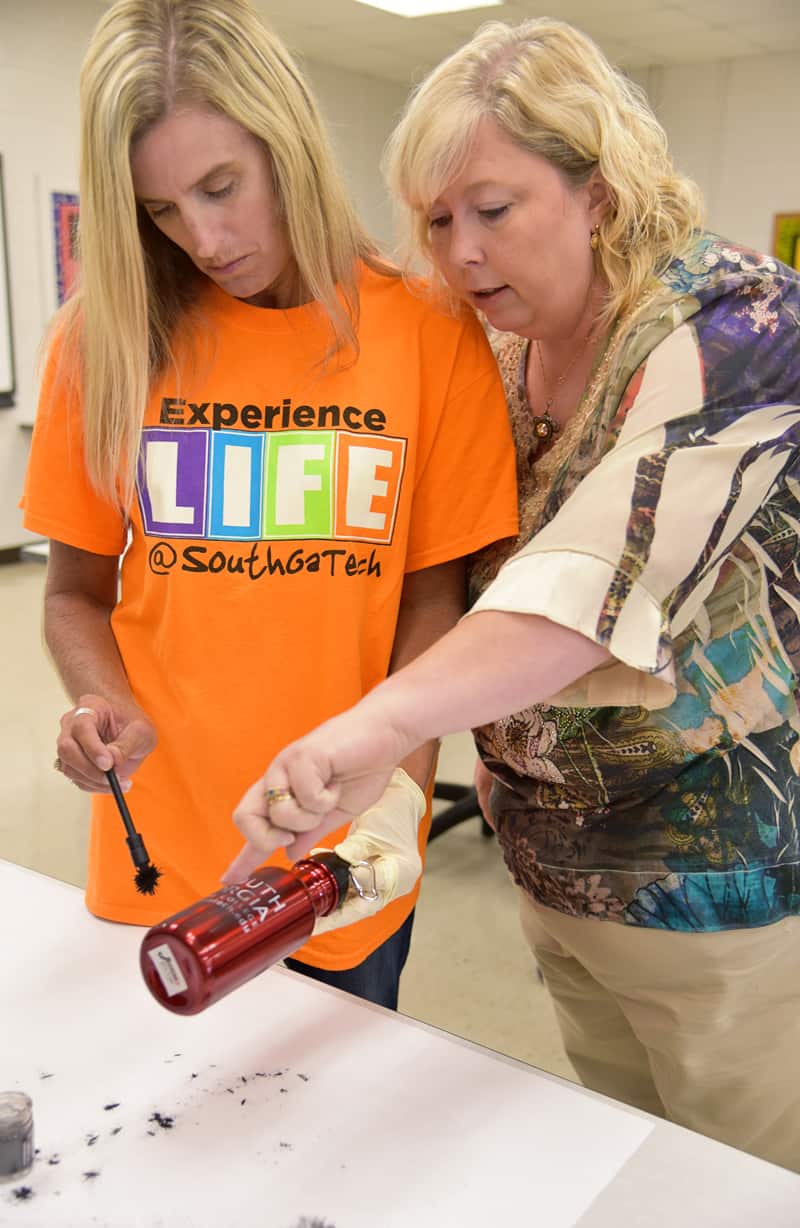 Criminal Justice instructor Teresa McCook shows a female student how to dust for finger prints on a bottle.