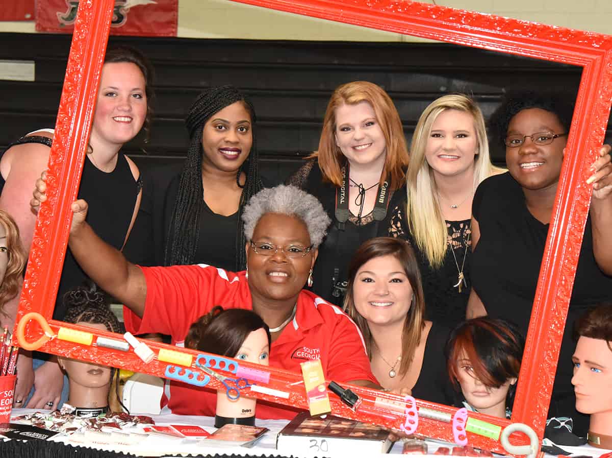 South Georgia Tech’s cosmetology instructor Dorothea McKenzie and her students are shown posing in a frame at the Cosmetology booth.