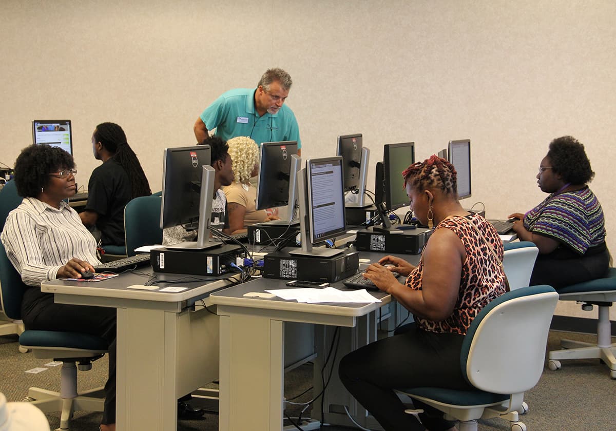 Rick Hughes (STANDING) of Ambassador helps job fair attendees apply for jobs at Wednesday’s job fair on SGTC’s campus in Cordele.