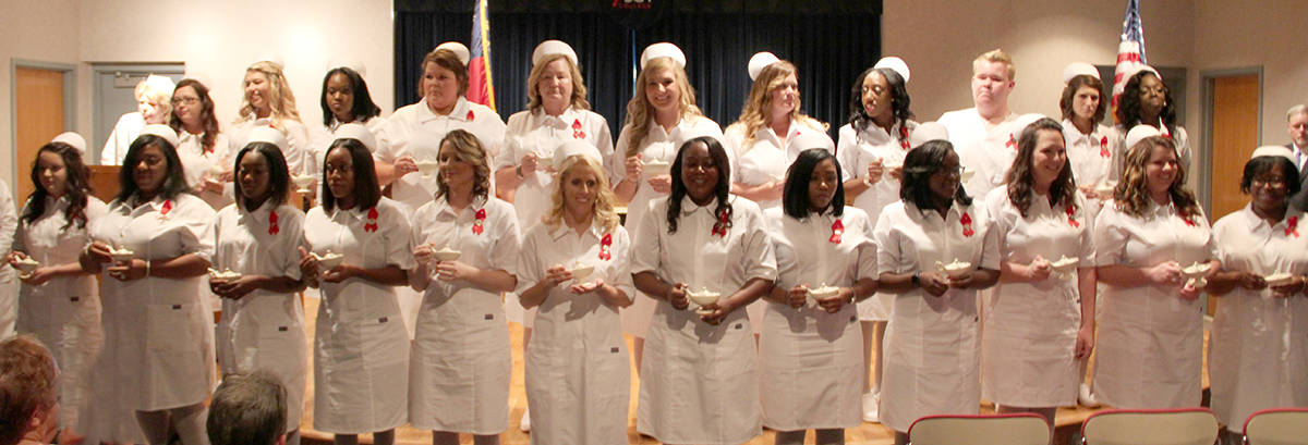 Nursing graduates pose with candles at ceremony