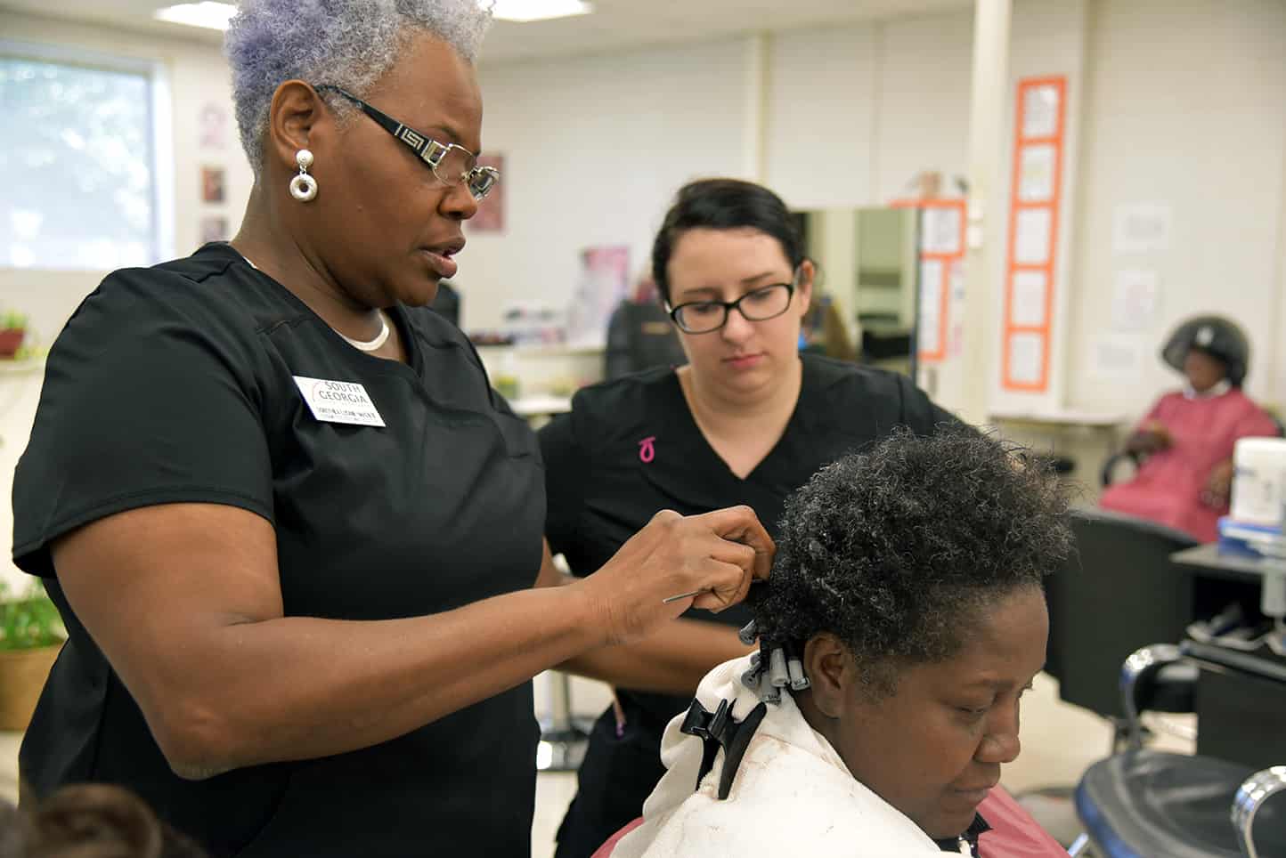 SGTC Cosmetology instructor Dorthea McKenzie (LEFT) is pictured with Destiny Baker (STANDING) working on a customer's hair. THE COSMETOLOGY PROGRAM WAS RECENTLY RECOGNIZED AS A TOP COSMETOLOGY PROGRAM IN THE COUNTRY for the second year in a row.
