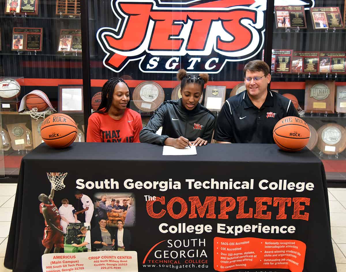 SGTC Lady Jet basketball player Houlfat Mahouchiza sits at a table between assistant coach Kezia Conyers and head coach James Frey.