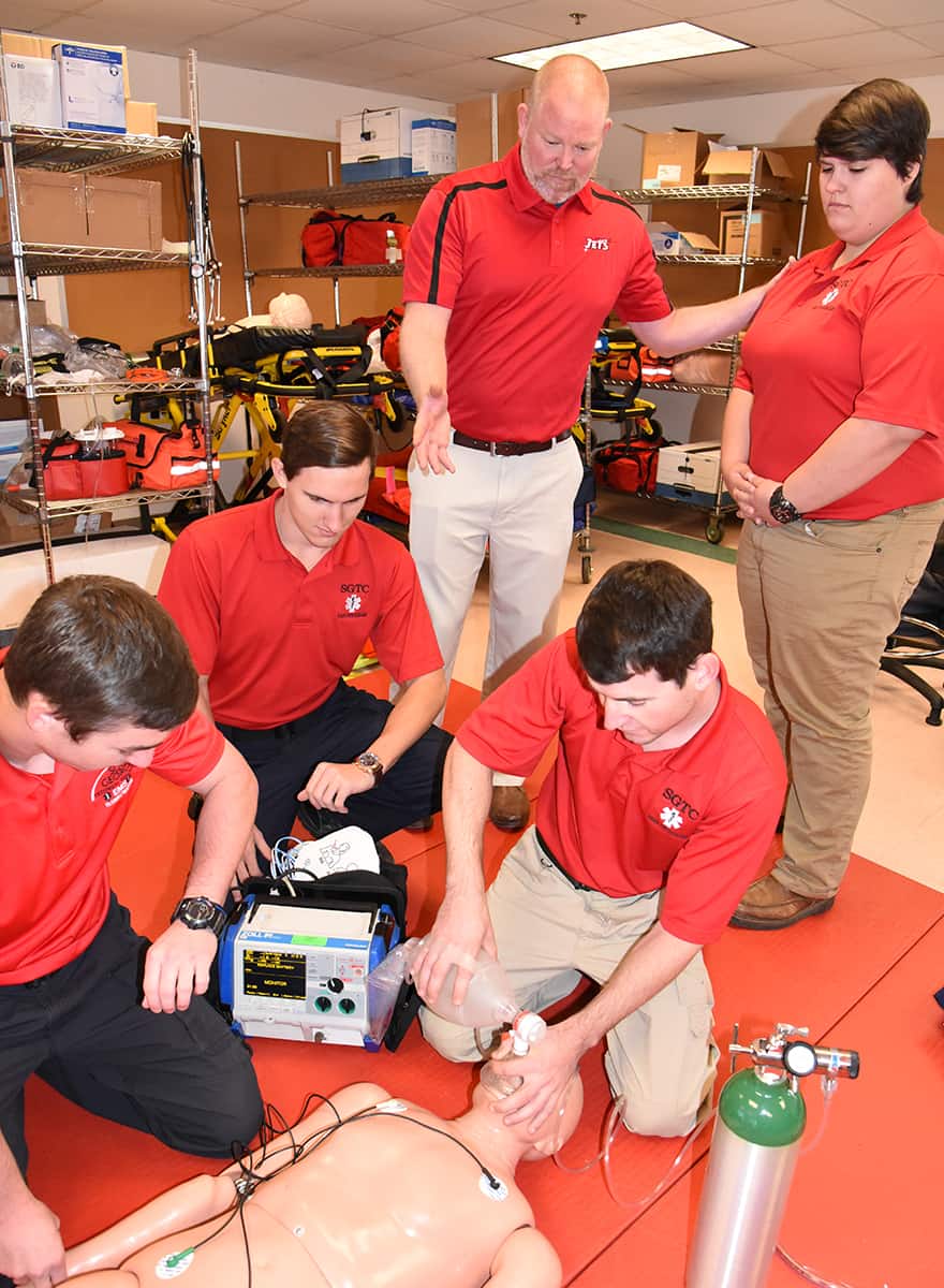 SGTC EMT Instructor Bryan Barnes is shown above standing (left) and talking with SGTC EMT students who are going through an exercise in the SGTC EMT lab area.