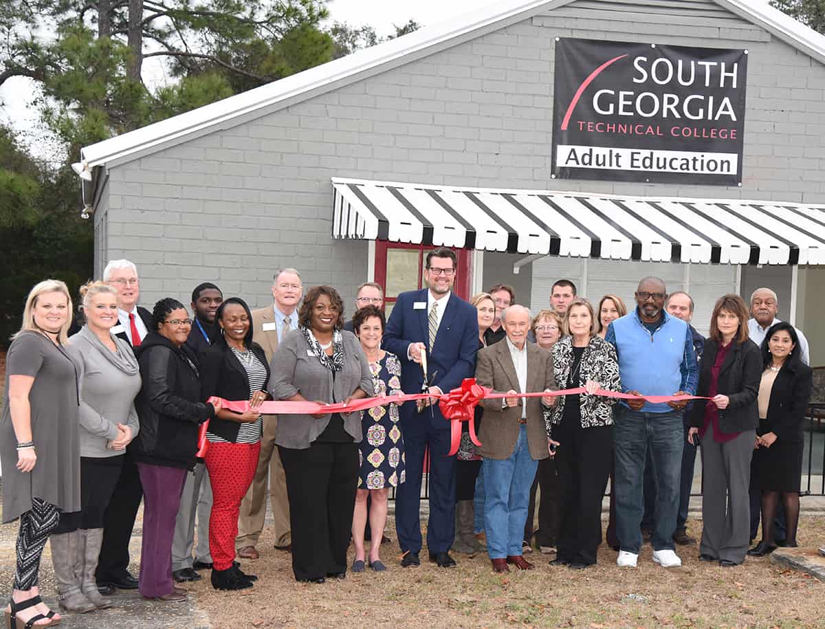 SGTC President Dr. John Watford (c) is shown above cutting the ribbon for the new South Georgia Technical College Adult Education site in Taylor County. Also shown with Dr. Watford are Taylor County Chamber of Commerce Director Amanda Haynie, Taylor County Executive Director Julie Kent and other chamber and county officials as well as South Georgia Technical College officials including Vice President of Economic Development Wally Summers, Assistant to the President Don Smith, Mia Collier, SGTC Adult Education Instructor for Taylor County, SGTC Dean of Adult Education Lillie Ann Winn, SGTC Vice President of Academic Affairs David Kuipers, and Kenia Wills of the SGTC Adult Education Department. Also shown with Dr. Watford is Jerry Weldon, Chairman of the Taylor County Board of Commissioners, Taylor County Manager Lenda Taunton, Assistant County Manager Shonda Blair, and Taylor County Schools Superintendent Jennifer Albritton. There was a great crowd that attended the open house and ribbon cutting.