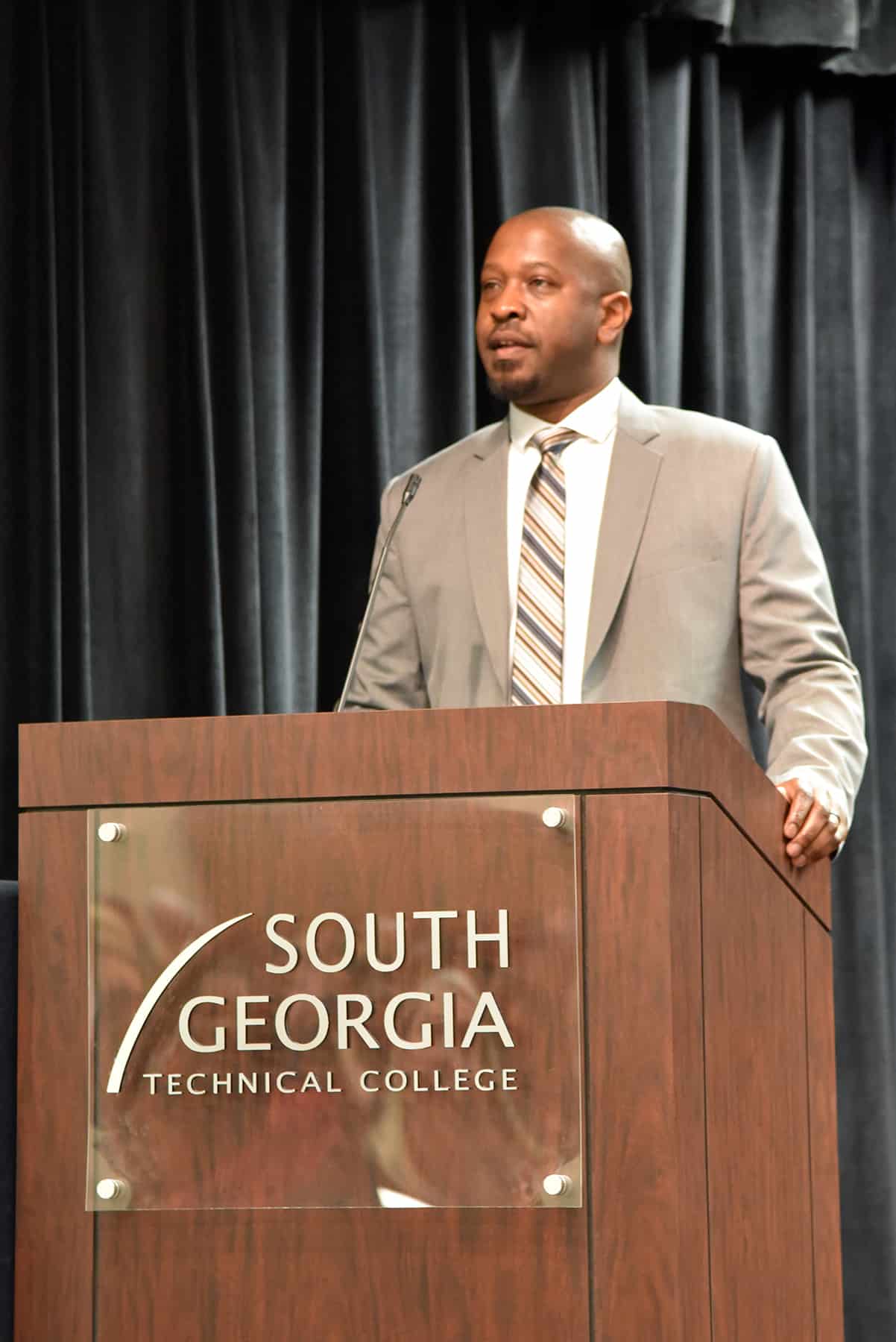 Ronny Roundtree stands behind a podium and delivers a speech during SGTC's Black History Month program