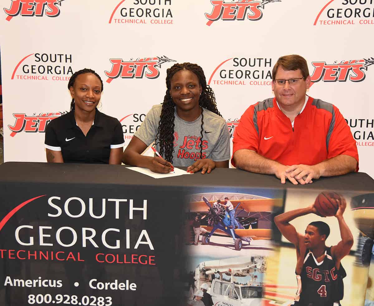 SGTC’s Esther “Nike” Adenike (c) is shown above signing a national letter of intent to play basketball at George Mason University. She is flanked by SGTC Assistant Coach Kezia Conyers (l) and SGTC head coach James Frey (r).