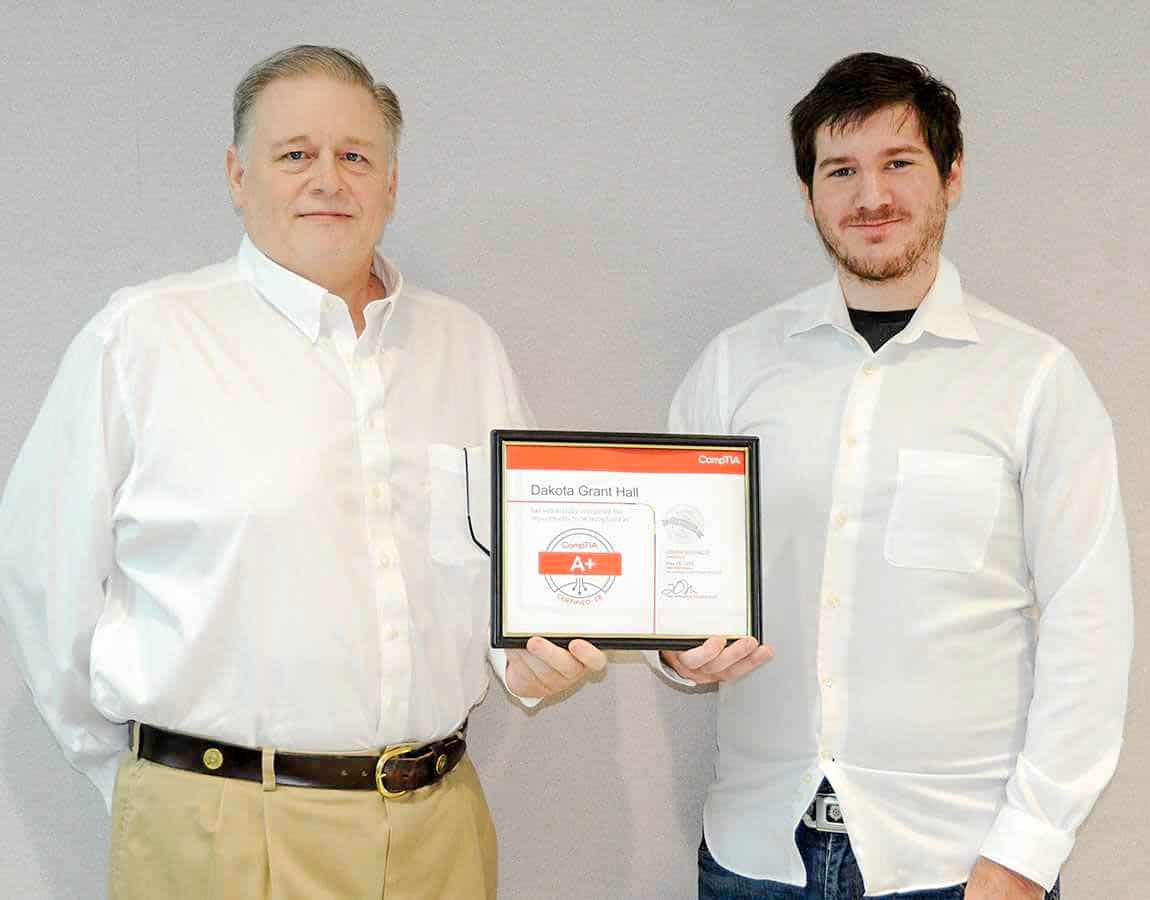 A man hands a certificate to another male.