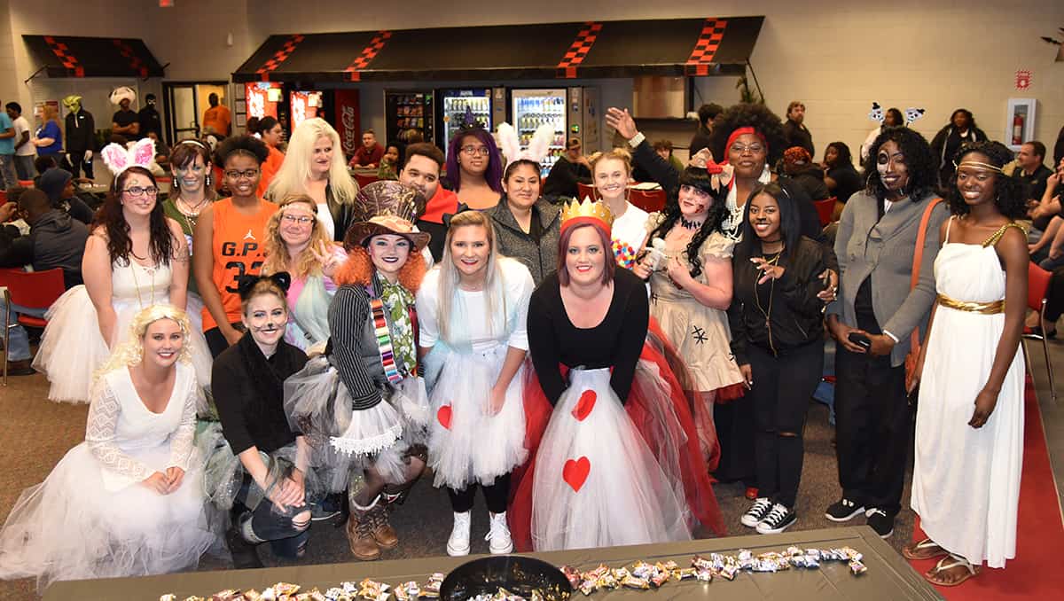 A group of people stand together in Halloween costumes.