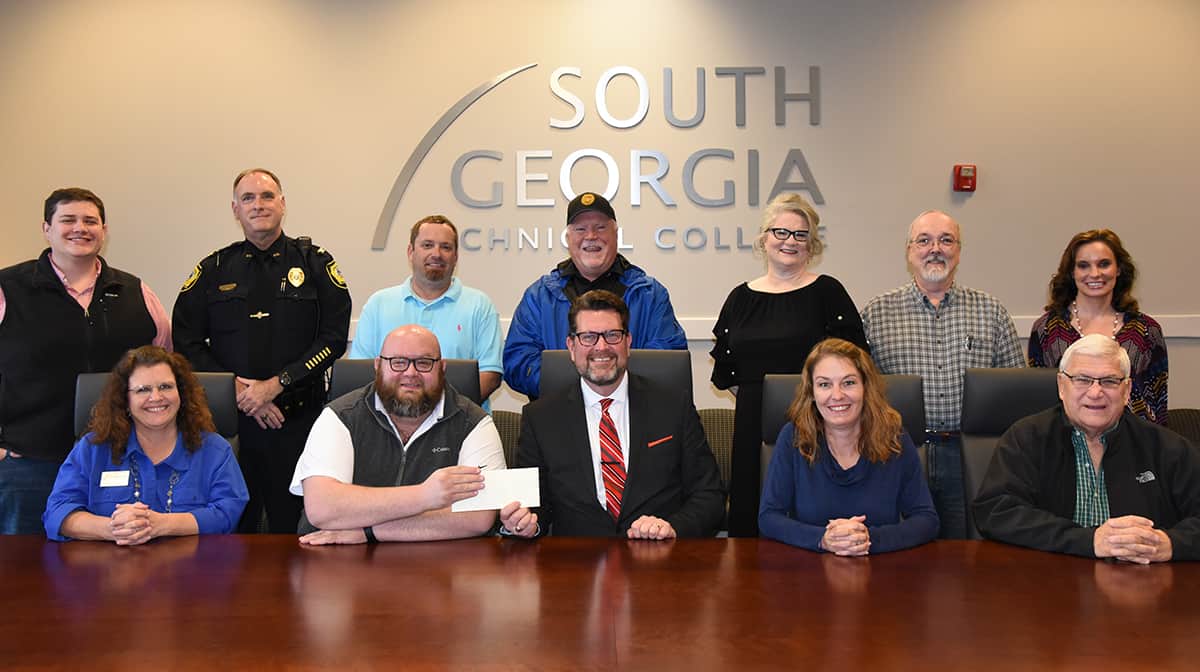 Nigel Poole (seated left center) is shown above presenting SGTC President Dr. John Watford (seated right center) with a scholarship check from the Smarr - Smith Foundation for an endowed scholarship at South Georgia Technical College. Also shown (l to r) seated with Poole and Dr. Watford are SGTC Academic Dean Vanessa Wall, Smarr-Smith Foundation Treasurer Jessie Simmons and Sumter County Sheriff Pete Smith. Standing (l to r) are: Smarr-Smith Foundation members Jimmy Whaley, Americus Police Chief Mark Scott, Blake Dukes, Mike Tracy, Tracy Hall, Donnie McCrary, and Faith Pinnell.