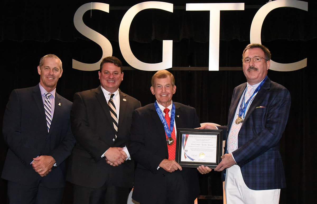 Boy Scouts of America South Georgia Council Development Director Sam McCord and South Georgia Council Scout Executive Matt Hart are shown above (l to r) with South Georgia Technical College President Emeritus Sparky Reeves who was recognized with the 2019 Outstanding Eagle Scout Award. Dr. Ben Andrews is shown presenting Reeves with the framed plaque.