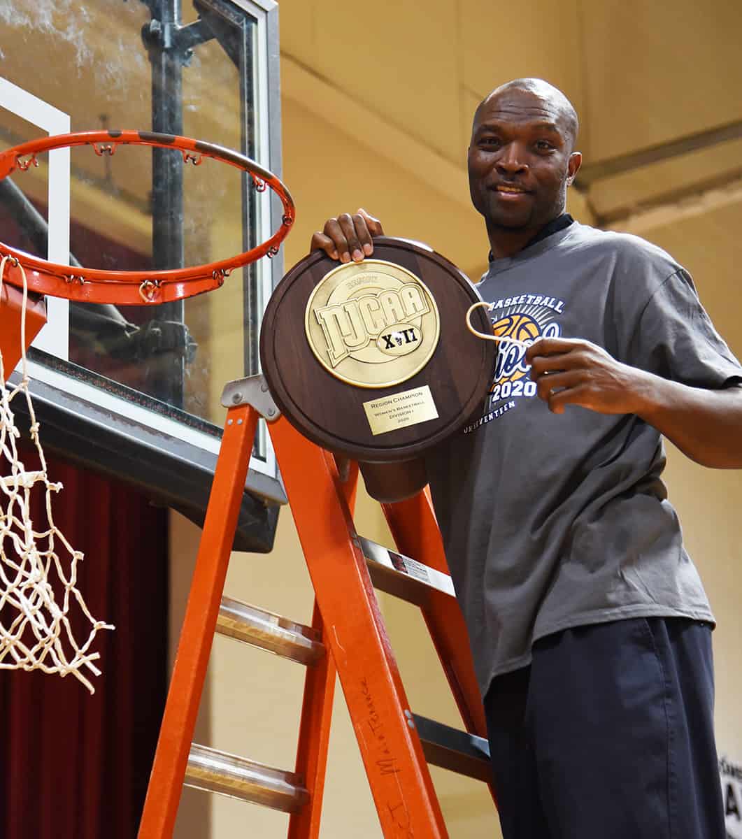 Demetrius Colson is shown above cutting down the net after the Lady Jets won the 2019 – 2020 NJCAA Region XVII championship.