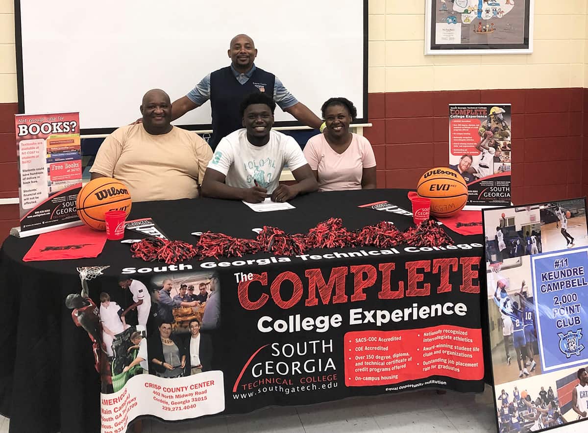 Webster County graduate Keundre Campbell (seated center) has signed a full-scholarship with the South Georgia Technical College Jets for the 2020 – 2021 season. Shown above seated (center) is Keundre Campbell with his father (left) Robert Campbell and his mother, (right) Debbie Merrit. Shown standing is WCHS Head Coach Keeyon Battle.