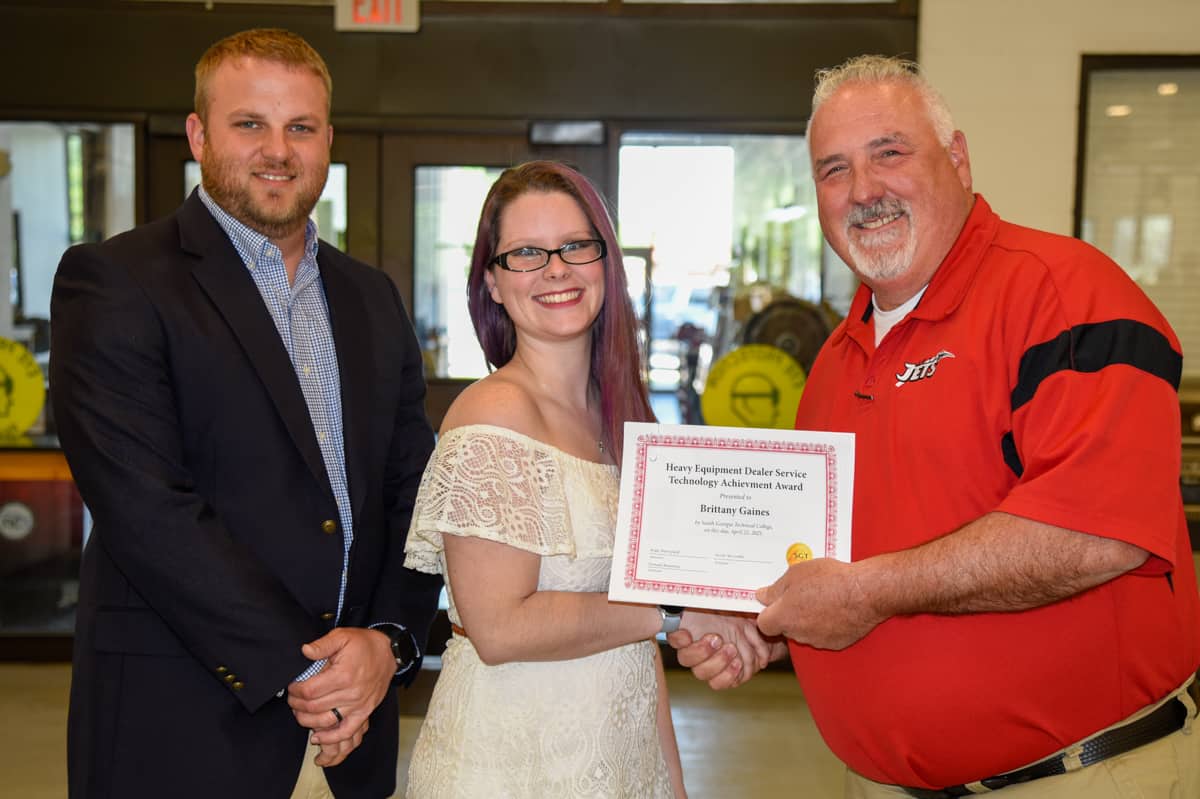 Instructors Kyle Hartsfield (left) and Don Rountree present an achievement award to student Brittany Gaines for her successful completion of the Heavy Equipment Dealer Service Technology program at South Georgia Technical College in Americus.