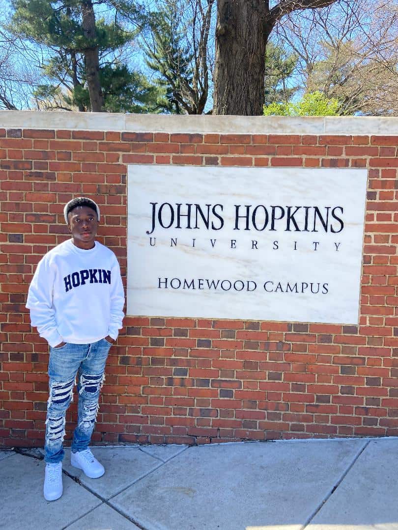 Chance Simpson is shown above in front of the John Hopkins University sign where he has been accepted and earned multiple scholarships.