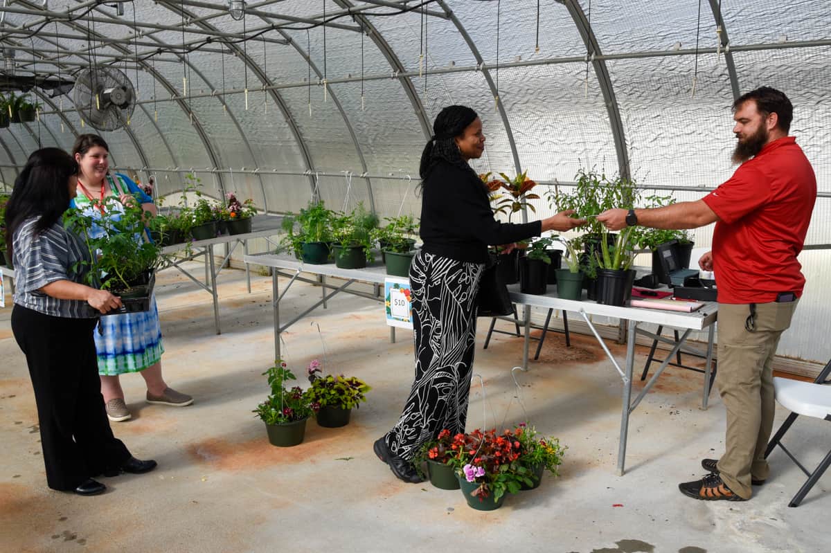 SGTC Horticulture instructor Brandon Gross (right) completes a transaction with SGTC Computer Information Systems instructor Andrea Ingram at the recent plant sale in the SGTC greenhouse.