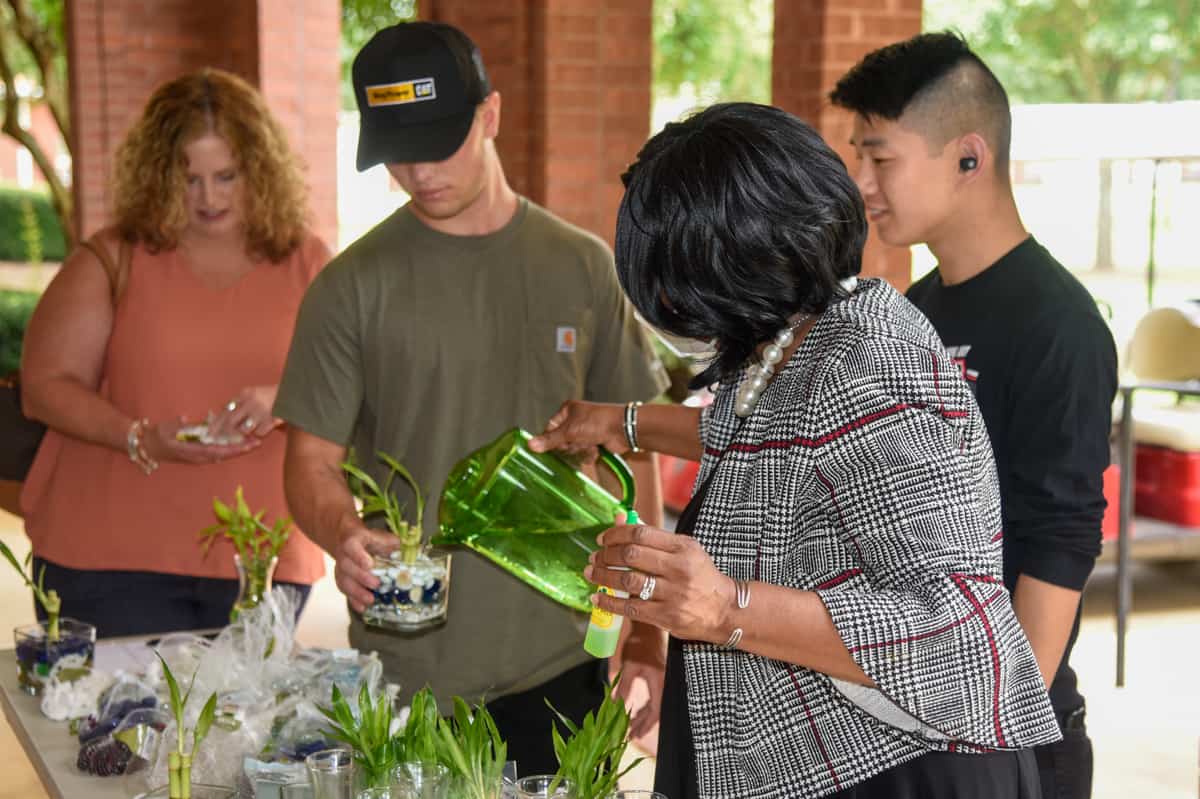 SGTC's Deo Cochran adds water to a student's "Lucky Bamboo" arrangement