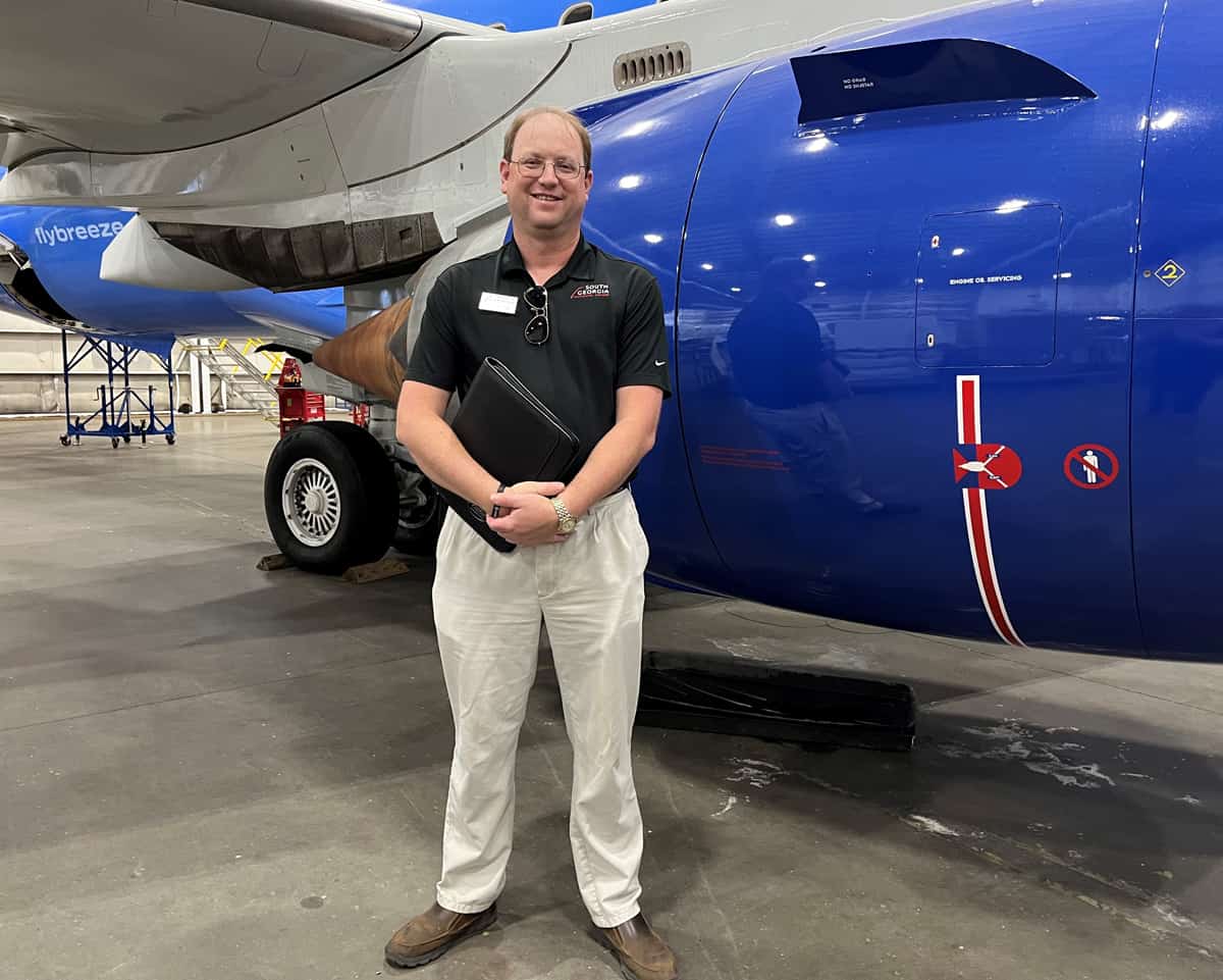 SGTC Aircraft Structural Technology Instructor Jason Wisham is shown above in front of one of the large aircrafts at the Embraer facility in Macon.