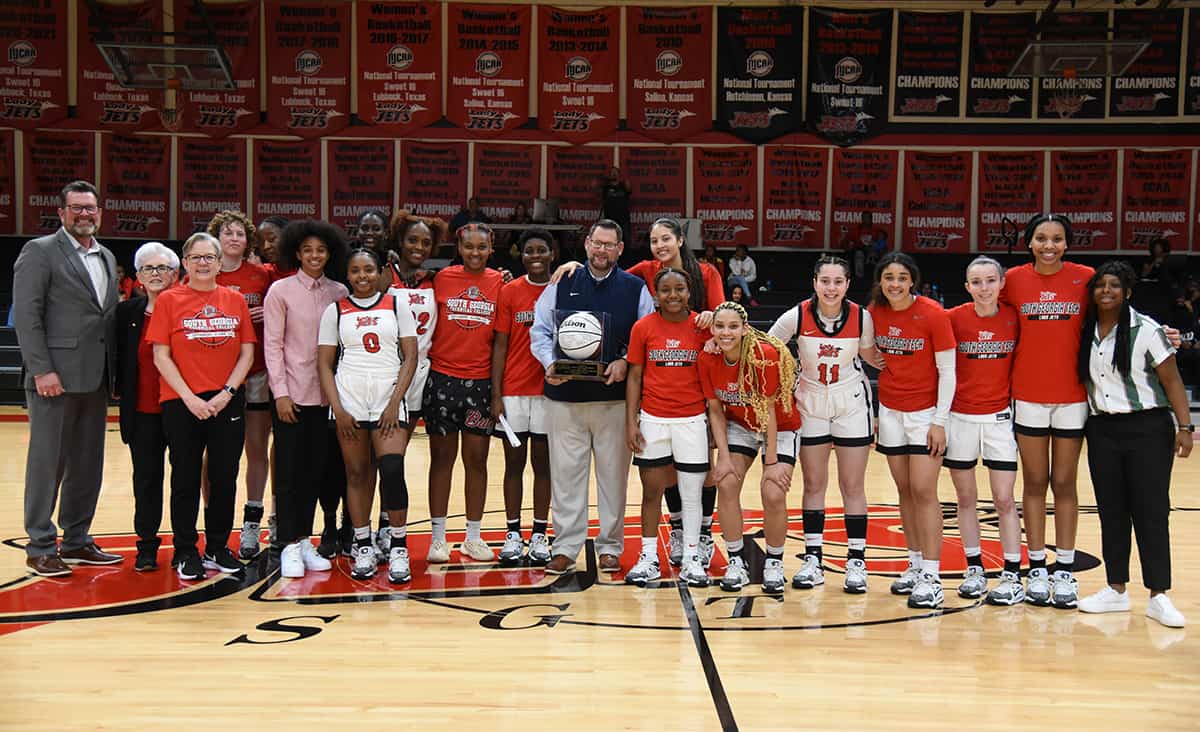 SGTC Lady Jets head coach James Frey is shown above with SGTC President Dr. John Watford and the 2022 – 2023 Lady Jets after he was presented with the signed basketball for his 300th career win.
