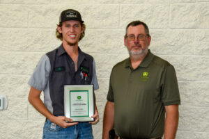 Instructor Matt Burks presents plaque to John Deere Ag Tech Graduate