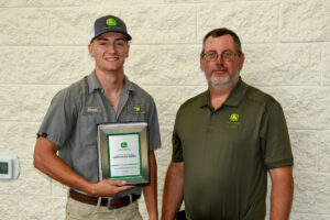 Instructor Matt Burks presents plaque to John Deere Ag Tech Graduate
