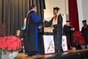 A student accepts his diploma from the president